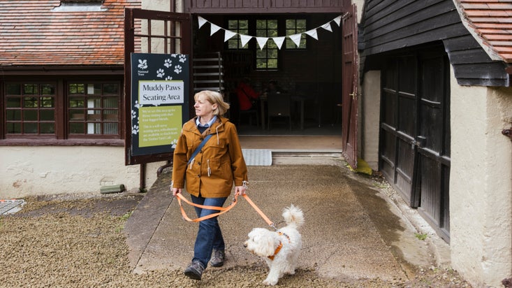 A visitor with their dog leaving the Muddy Paws café at Lyme Park, Cheshire